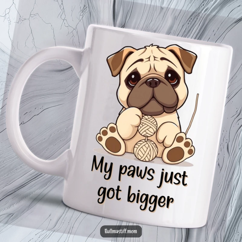 Funny Bullmastiff mug showing a giant-pawed dog hilariously tangled and playfully batting at a dangling ball of yarn.